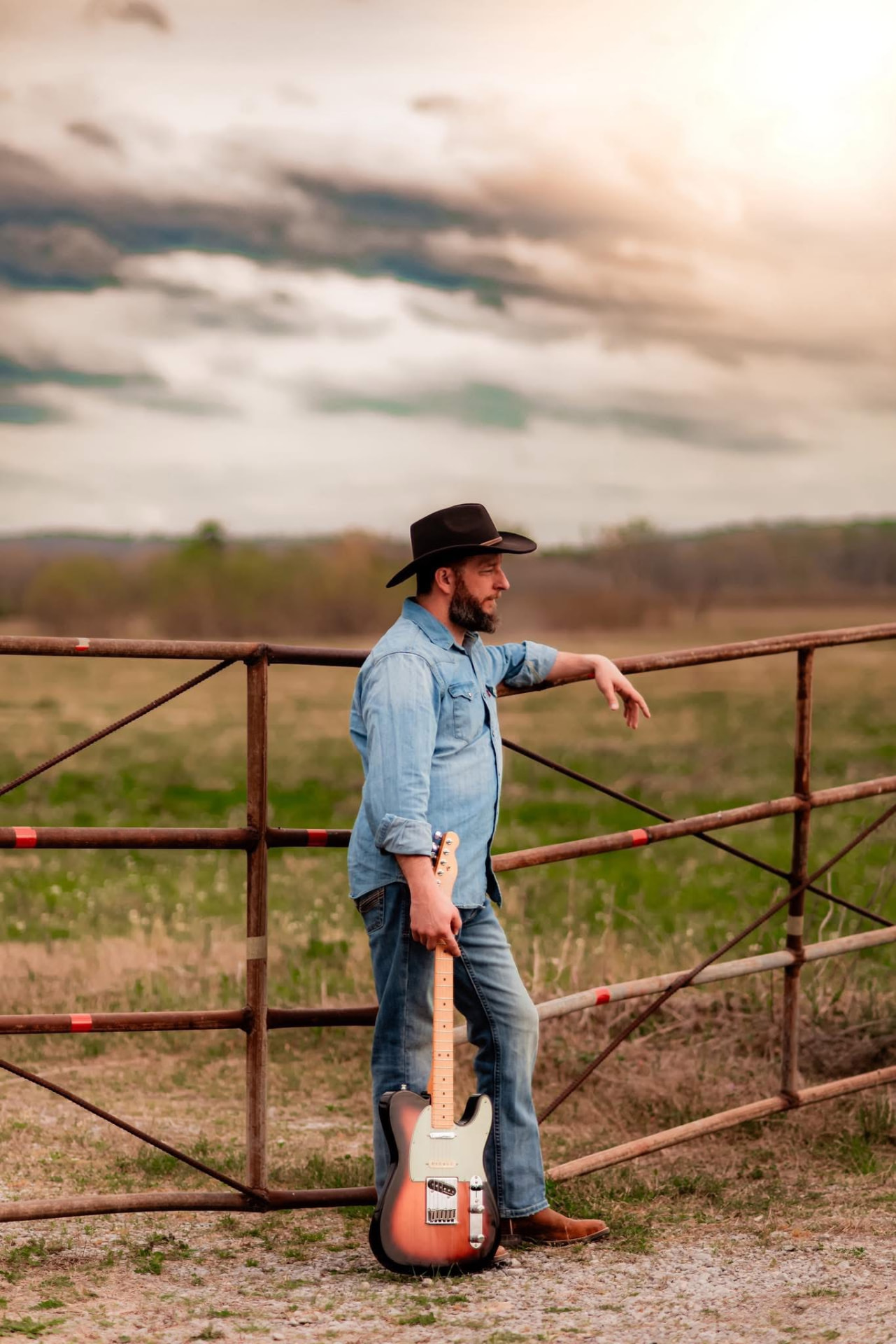 Nick leaning on a pasture gate at sunset